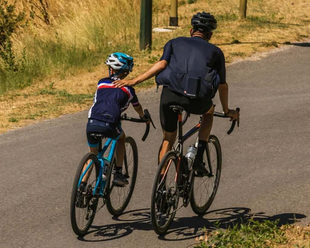 Un père fait du vélo avec son fils en l'aidant à avancer.